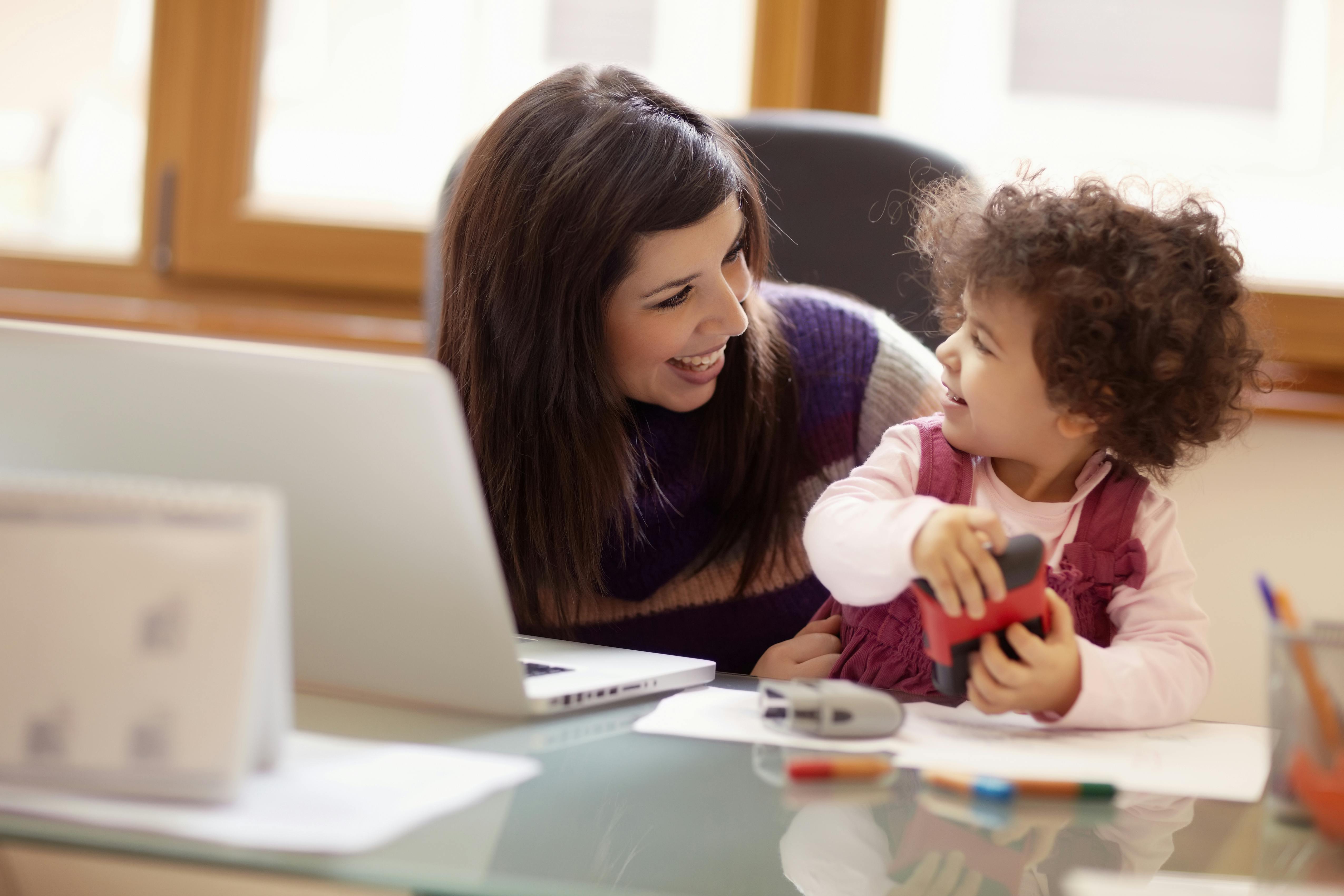 Une mère et sa fille interagissent joyeusement devant un ordinateur portable.