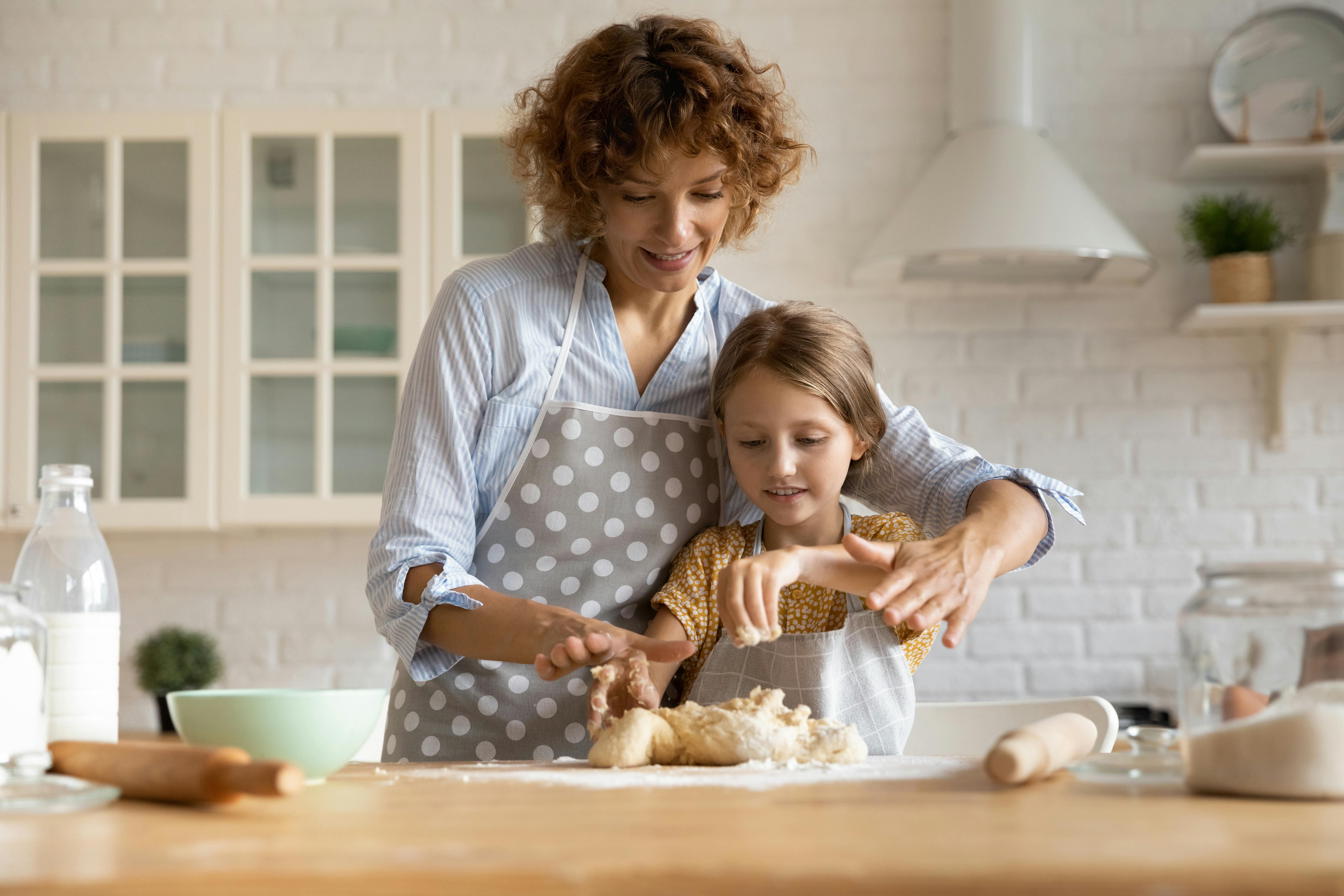 Une babysitter et une petite fille font de la pâtisserie dans une cuisine.