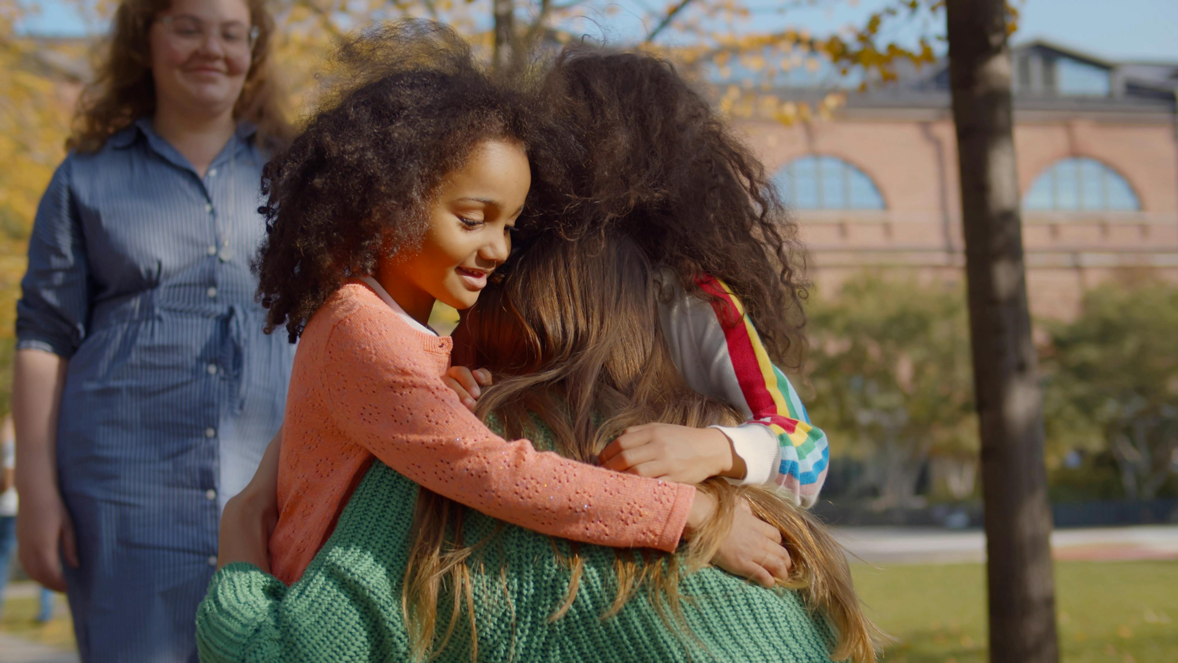 Deux filles font un câlin à leur mère avant de partir avec leur assistante maternelle.