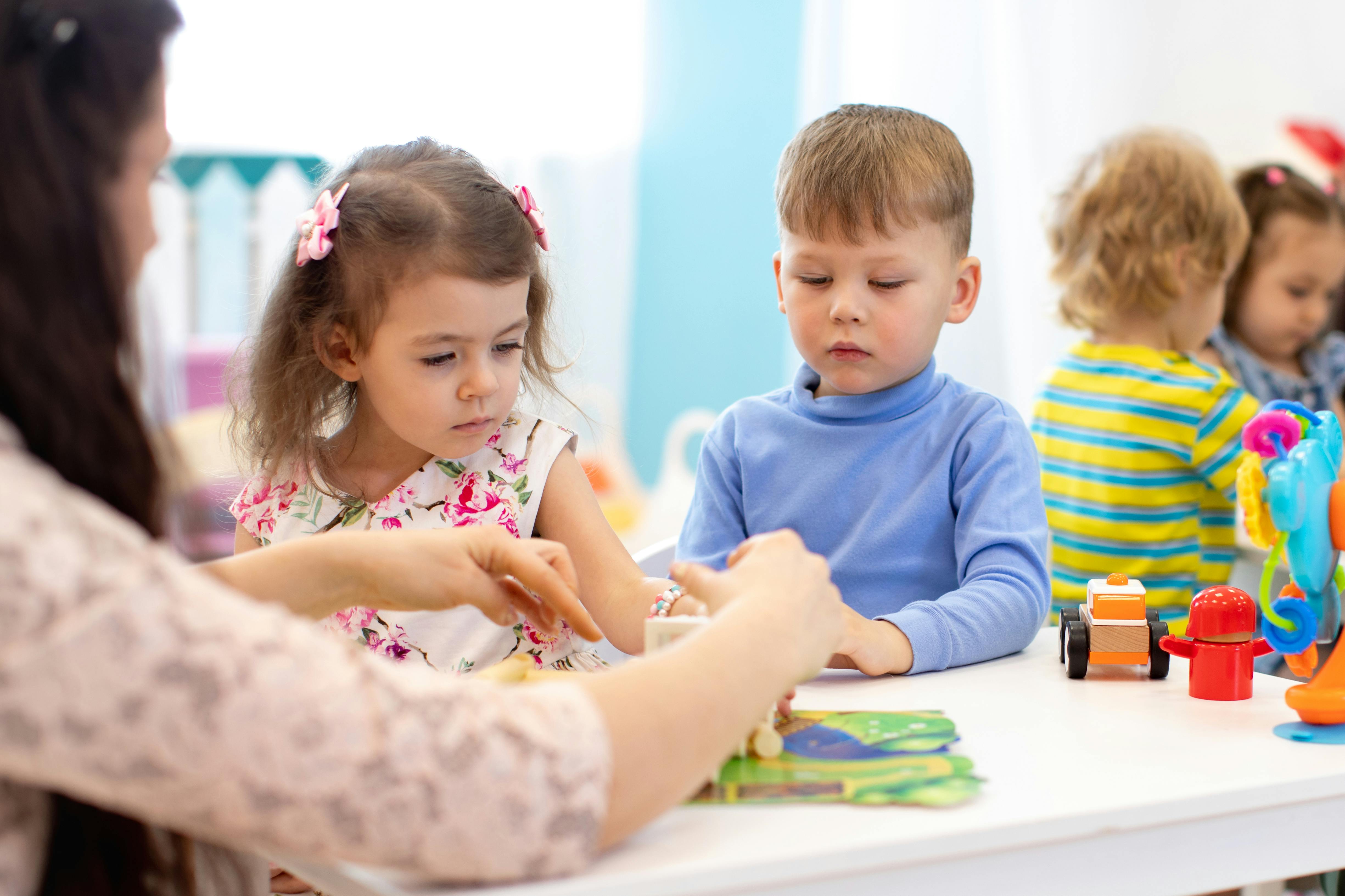 Une enseignante aide deux jeunes enfants à faire un puzzle.