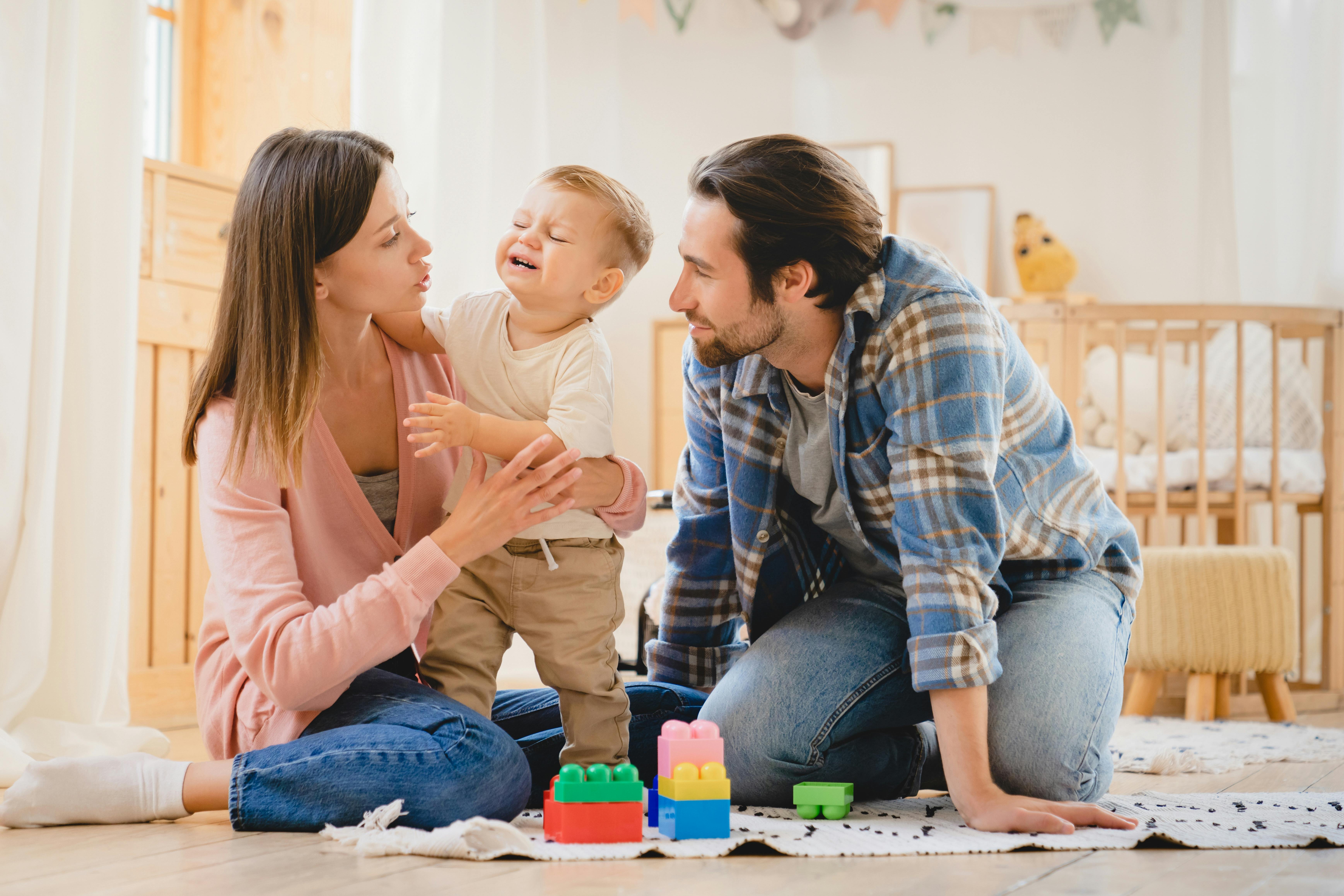 Une famille joue avec leur enfant dans une chambre lumineuse.