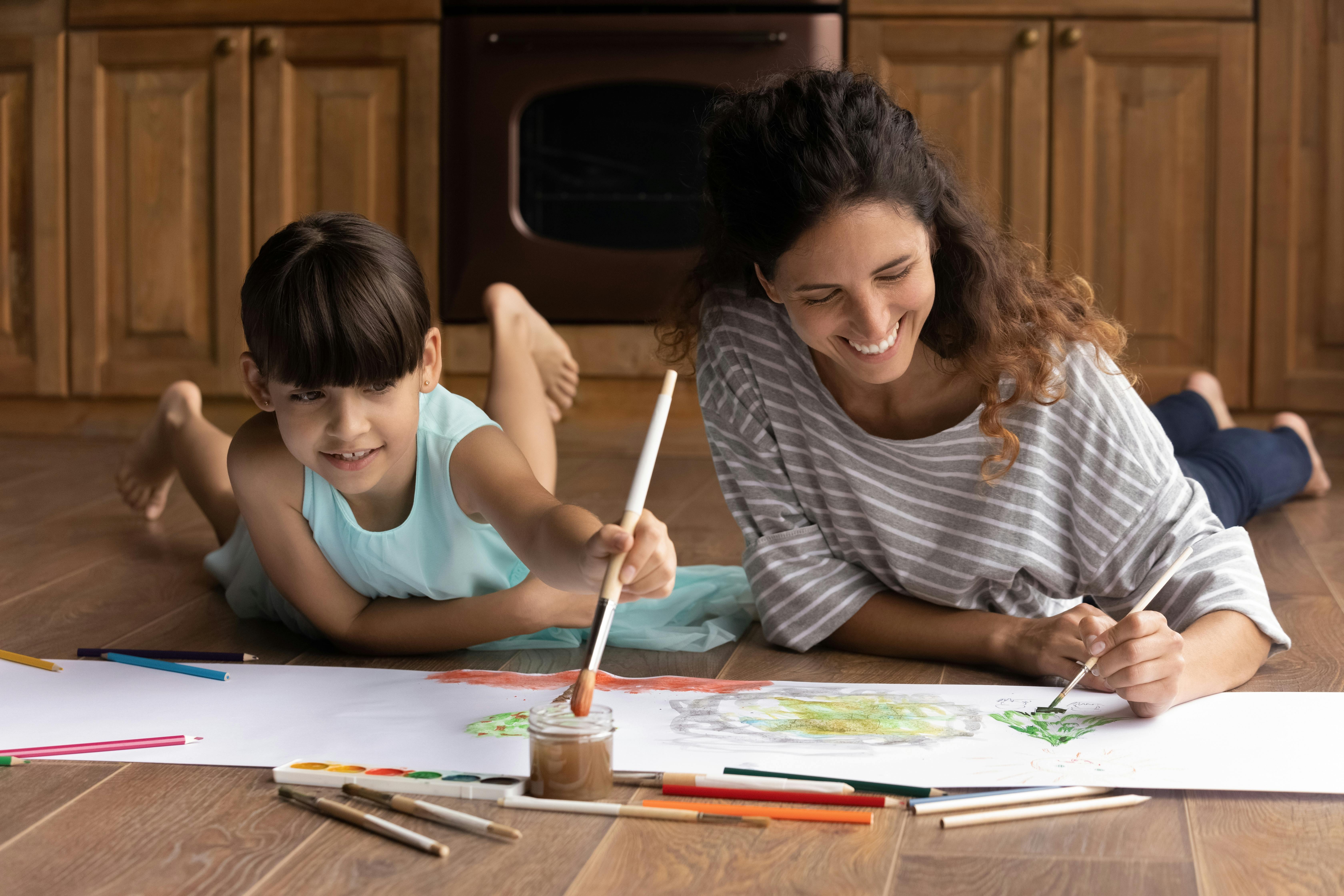 Une mère et son fils s'amusent à peindre sur le sol de la cuisine.